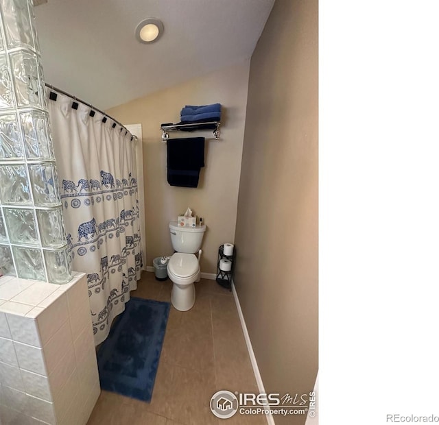 731 Bowen St, Longmont, CO 80501 - bathroom with tile patterned flooring, toilet, vaulted ceiling, a shower with curtain, and baseboards