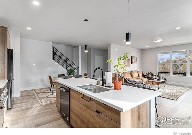 3580 W 62nd Pl, Denver, CO 80221 - kitchen with a sink, dishwashing machine, open floor plan, light wood-style floors, and a center island with sink