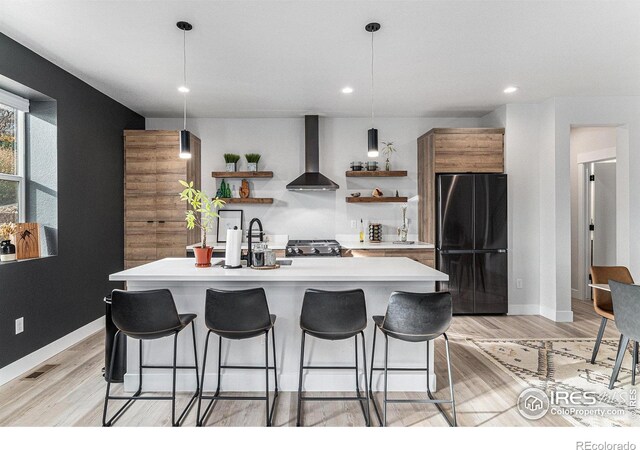 3580 W 62nd Pl, Denver, CO 80221 - kitchen featuring open shelves, freestanding refrigerator, wall chimney range hood, light countertops, and a breakfast bar