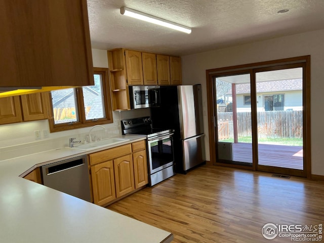 1126 Patricia Dr, Loveland, CO 80537 - kitchen featuring appliances with stainless steel finishes, a sink, a textured ceiling, open shelves, and healthy amount of natural light