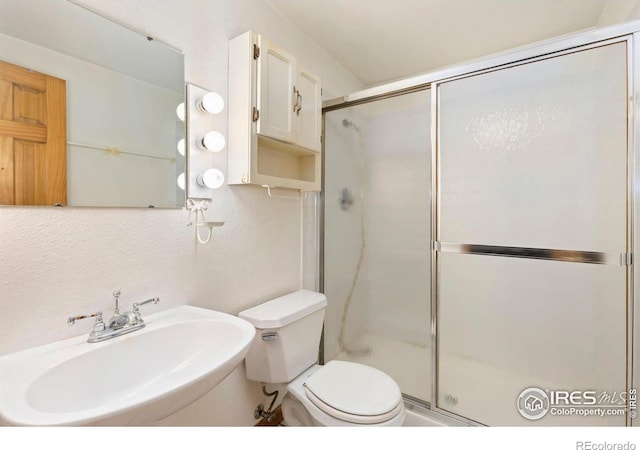 911 Timber Ct, Longmont, CO 80504 - bathroom featuring a sink, a stall shower, toilet, and a textured wall