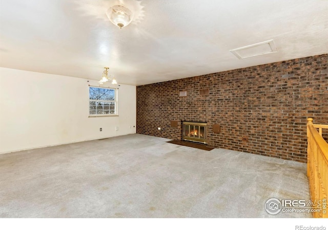911 Timber Ct, Longmont, CO 80504 - unfurnished living room featuring brick wall, carpet floors, a fireplace with flush hearth, a chandelier, and attic access