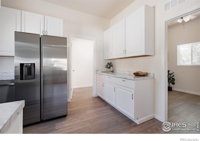 934 6th St, Berthoud, CO 80513 - kitchen featuring stainless steel fridge, light wood-type flooring, and white cabinets