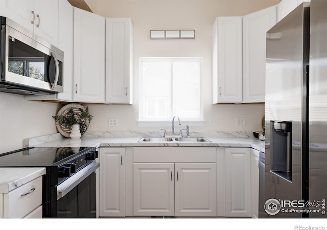 934 6th St, Berthoud, CO 80513 - kitchen featuring appliances with stainless steel finishes, a sink, white cabinetry, and light stone countertops