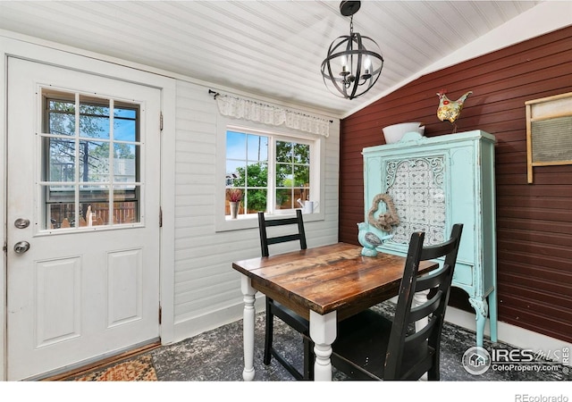 3730 Garfield Ave, Wellington, CO 80549 - dining area featuring vaulted ceiling, a chandelier, and wooden walls