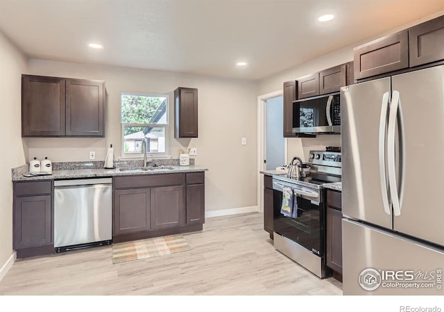 3014 High Dr, Evans, CO 80620 - kitchen featuring appliances with stainless steel finishes, a sink, light wood-style flooring, dark brown cabinetry, and light stone counters