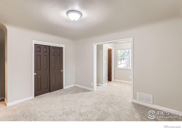 3014 High Dr, Evans, CO 80620 - unfurnished bedroom with carpet flooring, arched walkways, a textured ceiling, a closet, and baseboards