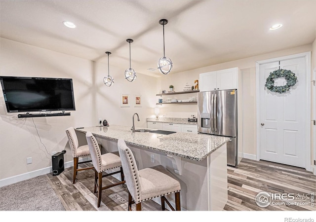 6253 Black Mesa Rd, Frederick, CO 80516 - kitchen featuring stainless steel refrigerator with ice dispenser, a breakfast bar, baseboards, white cabinets, and light wood-style floors