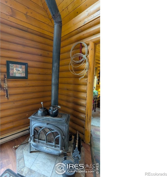 311 Chiricahua Cir, Red Feather Lakes, CO 80545 - detailed view of a wood stove, a baseboard heating unit, log walls, and wood finished floors