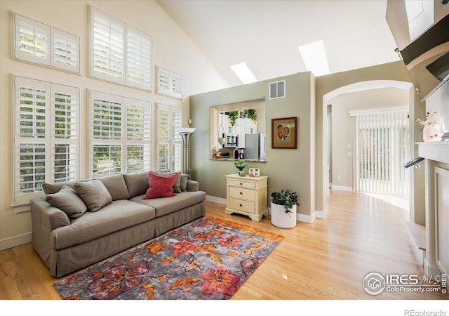 2758 Meadow Mountain Trl, Lafayette, CO 80026 - living area with high vaulted ceiling, a skylight, light wood-style flooring, arched walkways, and baseboards