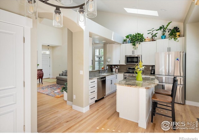 2758 Meadow Mountain Trl, Lafayette, CO 80026 - kitchen with stainless steel appliances, light wood-style floors, a skylight, lofted ceiling, and light stone counters