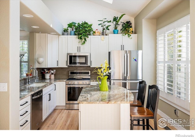 2758 Meadow Mountain Trl, Lafayette, CO 80026 - kitchen with stainless steel appliances, a sink, a center island, tasteful backsplash, and light wood-type flooring