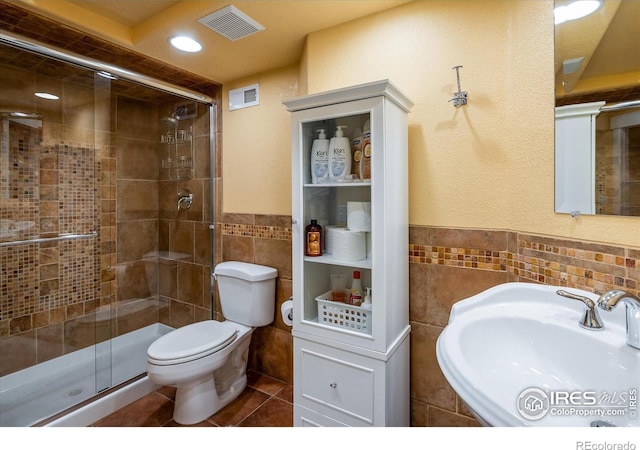 2758 Meadow Mountain Trl, Lafayette, CO 80026 - bathroom featuring tile walls, a sink, toilet, a stall shower, and tile patterned floors