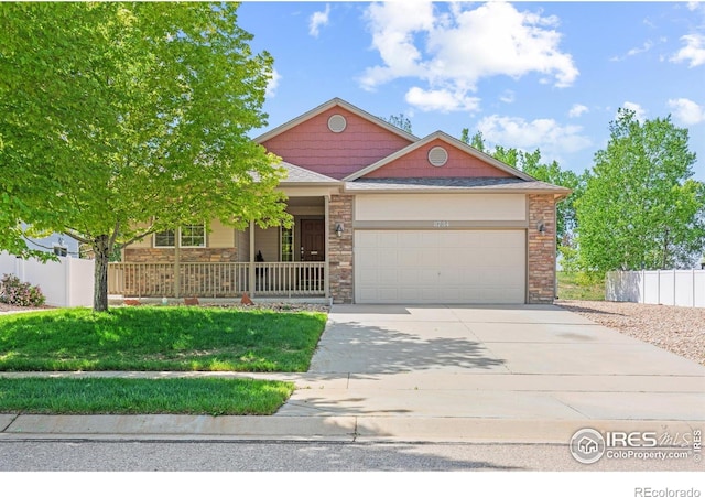 8734 19th Street Rd, Greeley, CO 80634 - view of front of home featuring an attached garage, concrete driveway, stone siding, and covered porch