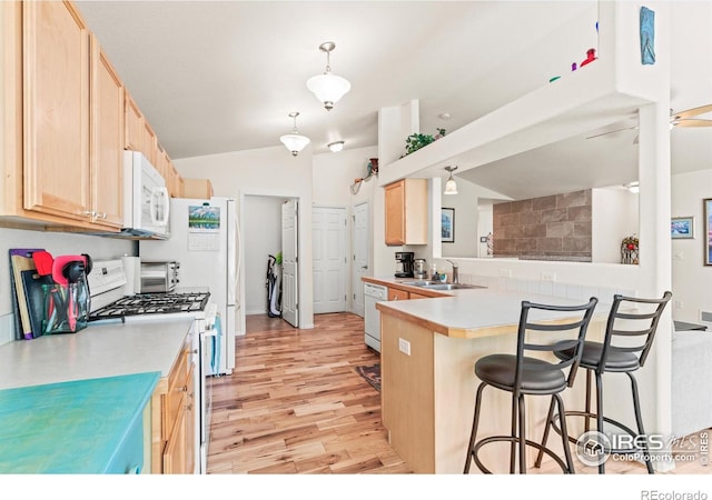 8734 19th Street Rd, Greeley, CO 80634 - kitchen featuring white appliances, light brown cabinets, a sink, lofted ceiling, and a breakfast bar