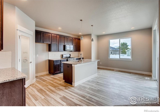 1128 N 5th St, Johnstown, CO 80534 - kitchen featuring stainless steel microwave, gas range, baseboards, dark brown cabinetry, and recessed lighting