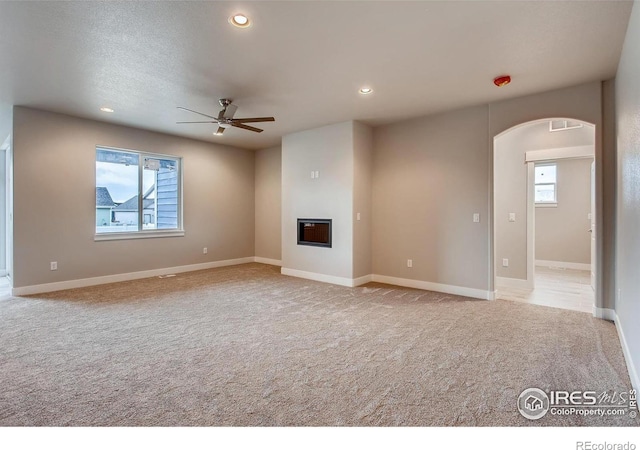 1128 N 5th St, Johnstown, CO 80534 - unfurnished living room with ceiling fan, arched walkways, carpet, a glass covered fireplace, and recessed lighting
