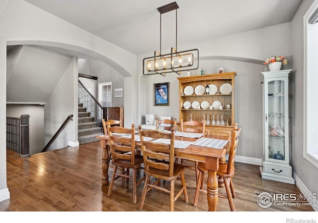7427 Couples Ct, Fort Collins, CO 80528 - dining room featuring arched walkways, wood finished floors, stairs, a chandelier, and baseboards
