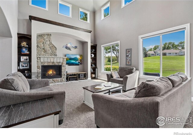 7427 Couples Ct, Fort Collins, CO 80528 - living area with built in shelves, a stone fireplace, carpet flooring, a high ceiling, and baseboards