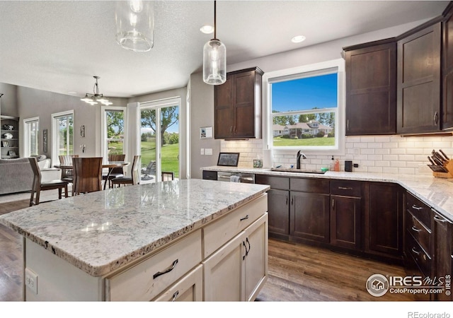 7427 Couples Ct, Fort Collins, CO 80528 - kitchen with a sink, wood finished floors, dark brown cabinets, decorative backsplash, and light stone counters
