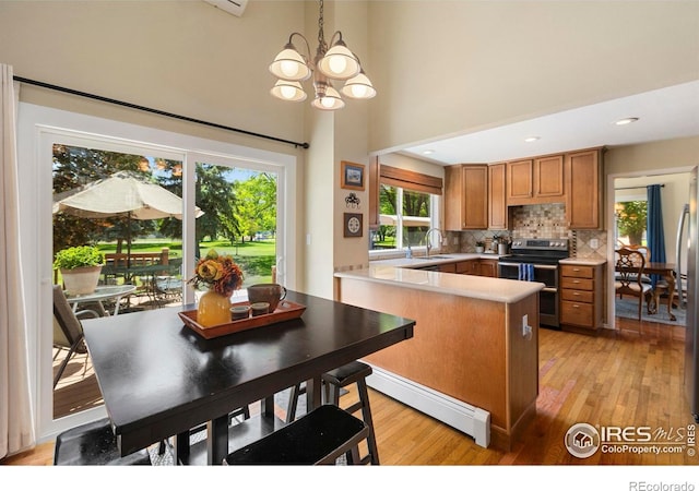 3804 Amy Pl, Loveland, CO 80538 - kitchen featuring range with two ovens, baseboard heating, a peninsula, a chandelier, and brown cabinets