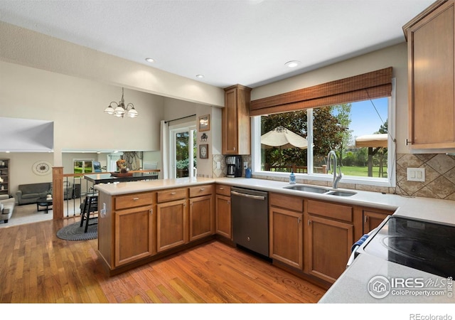 3804 Amy Pl, Loveland, CO 80538 - kitchen with stainless steel dishwasher, a sink, a peninsula, brown cabinetry, and light countertops