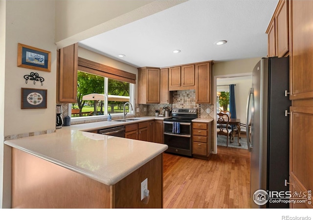 3804 Amy Pl, Loveland, CO 80538 - kitchen with stainless steel appliances, a sink, a peninsula, backsplash, and light wood-style flooring