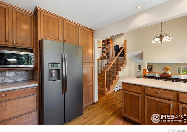 3804 Amy Pl, Loveland, CO 80538 - kitchen with appliances with stainless steel finishes, light wood finished floors, a chandelier, brown cabinets, and light countertops