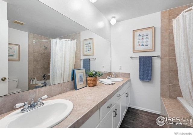 3804 Amy Pl, Loveland, CO 80538 - bathroom with toilet, double vanity, wood finished floors, baseboards, and tiled shower / bath combo