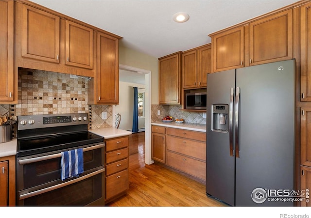 3804 Amy Pl, Loveland, CO 80538 - kitchen featuring appliances with stainless steel finishes, light wood-style flooring, light countertops, brown cabinetry, and backsplash
