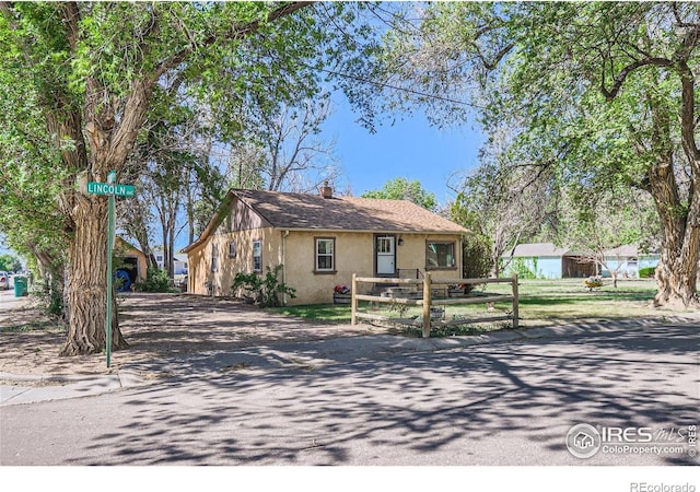 3833 Lincoln Ave, Wellington, CO 80549 - view of front of property with stucco siding, driveway, and a chimney