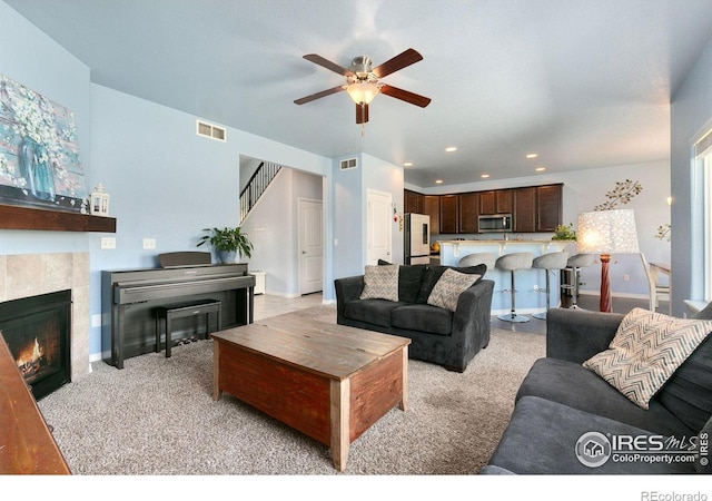 5664 Osbourne Dr, Windsor, CO 80550 - living area with a ceiling fan, a tiled fireplace, recessed lighting, baseboards, and light carpet