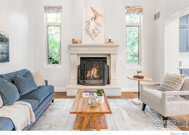 609 Corona Ct, Lafayette, CO 80026 - living area featuring wood finished floors, a warm lit fireplace, plenty of natural light, and baseboards