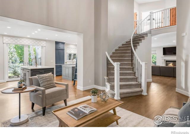 609 Corona Ct, Lafayette, CO 80026 - living area featuring a towering ceiling, stairway, light wood-type flooring, baseboards, and a glass covered fireplace