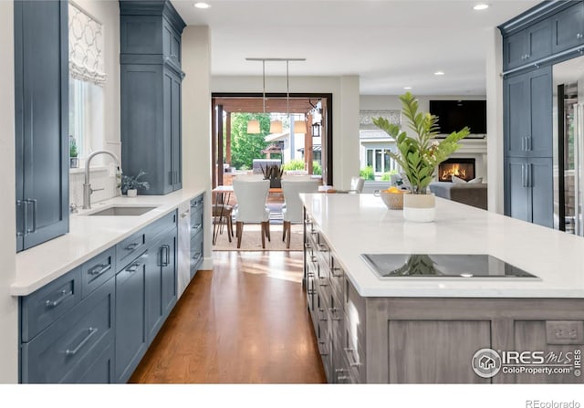 609 Corona Ct, Lafayette, CO 80026 - kitchen with a sink, black electric cooktop, wood finished floors, a warm lit fireplace, and a kitchen island