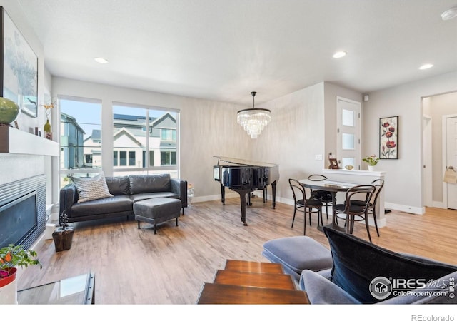 6211 Stable View St, Castle Pines, CO 80108 - living room featuring a tile fireplace, wood finished floors, healthy amount of natural light, a chandelier, and recessed lighting