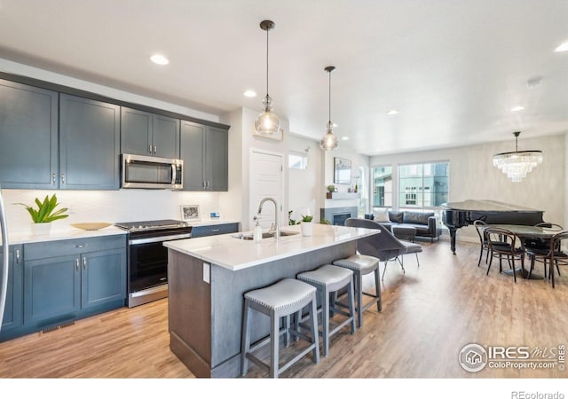 6211 Stable View St, Castle Pines, CO 80108 - kitchen featuring stainless steel appliances, a sink, light wood finished floors, a kitchen breakfast bar, and light countertops