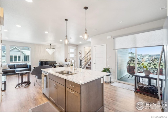 6211 Stable View St, Castle Pines, CO 80108 - kitchen with a sink, open floor plan, stainless steel dishwasher, light wood-style flooring, and hanging light fixtures