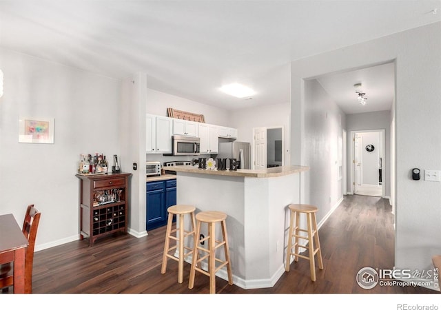 4451 S Ammons St Unit 307, Littleton, CO 80123 - kitchen with blue cabinets, appliances with stainless steel finishes, a kitchen bar, and dark wood-style flooring