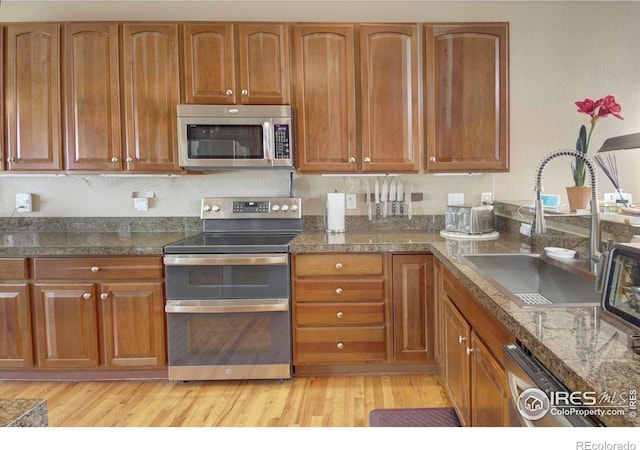 2085 Tundra Cir, Erie, CO 80516 - kitchen featuring stainless steel appliances, a sink, light wood-style flooring, and brown cabinets