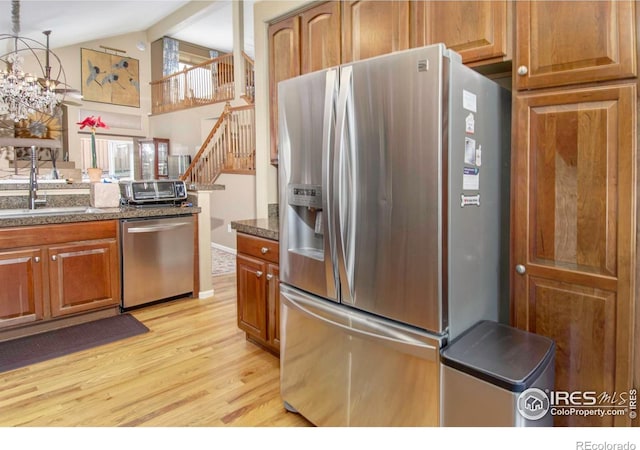2085 Tundra Cir, Erie, CO 80516 - kitchen featuring stainless steel appliances, light wood-style floors, brown cabinets, a sink, and dark stone countertops