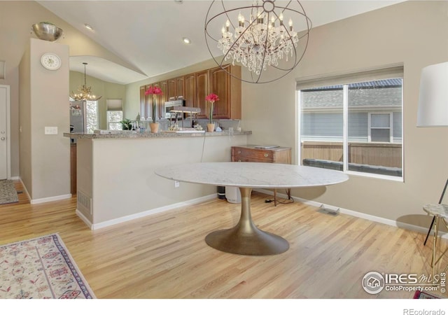 2085 Tundra Cir, Erie, CO 80516 - dining area with a chandelier, light wood-style flooring, vaulted ceiling, and baseboards