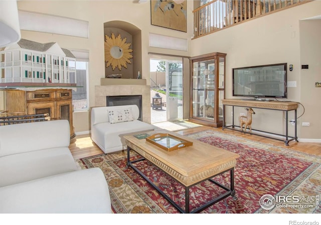 2085 Tundra Cir, Erie, CO 80516 - living room featuring a fireplace, wood finished floors, baseboards, and a high ceiling