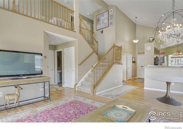 2085 Tundra Cir, Erie, CO 80516 - living area featuring high vaulted ceiling, a chandelier, stairway, wood finished floors, and baseboards
