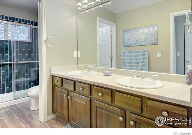 2085 Tundra Cir, Erie, CO 80516 - bathroom with toilet, double vanity, wood finished floors, and a shower stall