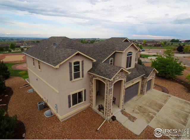 3106 Megan Way, Berthoud, CO 80513 - view of front of property featuring stone siding, stucco siding, a shingled roof, an attached garage, and central AC
