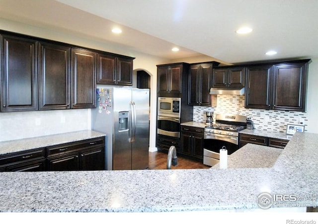 3106 Megan Way, Berthoud, CO 80513 - kitchen featuring stainless steel appliances, under cabinet range hood, tasteful backsplash, arched walkways, and recessed lighting