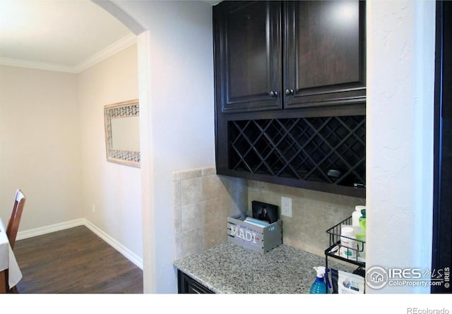 3106 Megan Way, Berthoud, CO 80513 - kitchen with arched walkways, crown molding, tasteful backsplash, dark wood-type flooring, and light stone counters