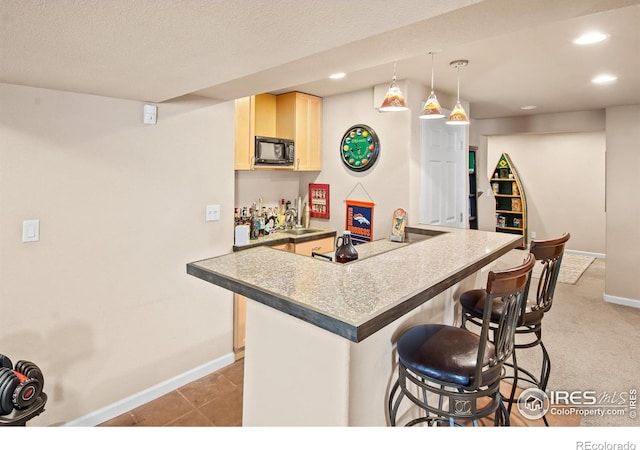 23570 E Holly Hills Way, Parker, CO 80138 - kitchen featuring black microwave, a breakfast bar area, light brown cabinets, a sink, and baseboards