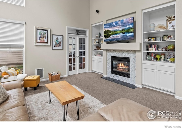23570 E Holly Hills Way, Parker, CO 80138 - living room featuring carpet flooring, a fireplace, french doors, a towering ceiling, and baseboards